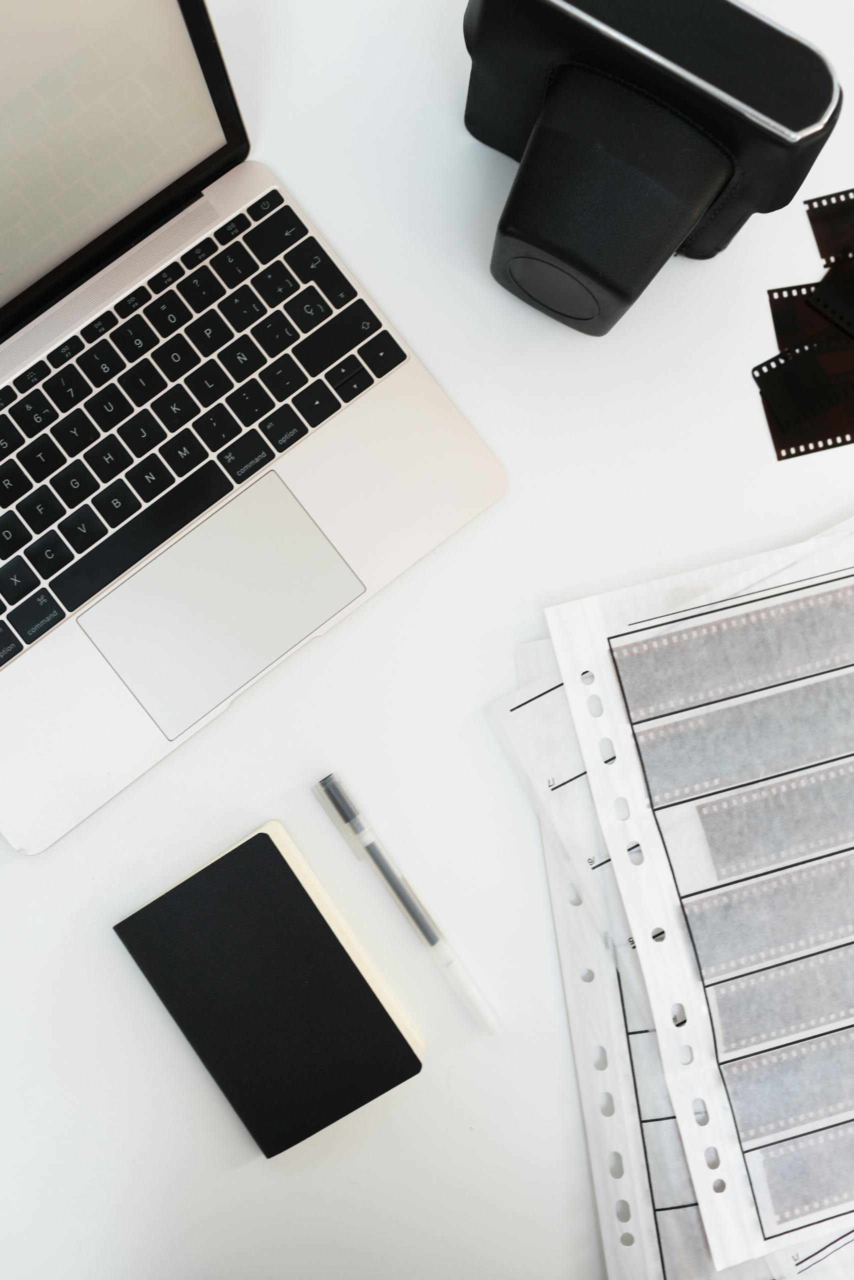 A clean desktop featuring a laptop, vintage camera, and film negatives in a modern workspace.