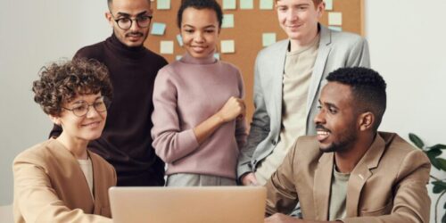 Photo by fauxels A diverse group of professionals collaborating around a laptop in an office setting.